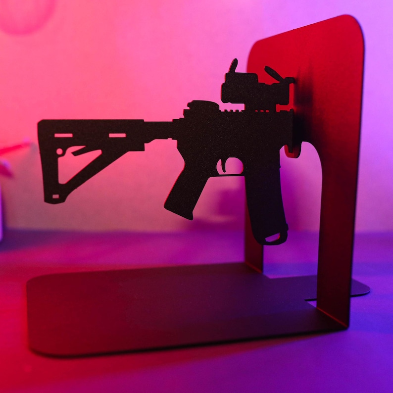 May include: A black metal bookend shaped like a rifle with a red base. The bookend is a decorative item for a home or office.