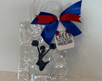 May include: Clear plastic gift bag with a black cheerleader silhouette and pom-poms. The bag has a blue and red bow and a tag that reads "It's a Cheer Thing You Wouldn't Understand."