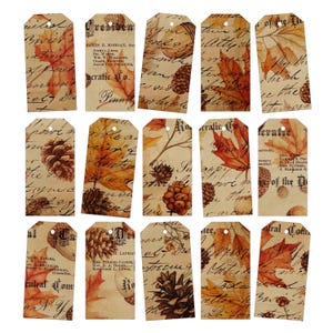 May include: A collection of fifteen vintage-style gift tags. Each tag features a sepia-toned background with autumn leaves, pinecones, and handwritten script. Some tags include text such as "Geratic Co." and names. The tags have a hole at the top for stringing.