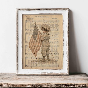 May include: Framed print featuring a vintage illustration of a child holding an American flag. The artwork is set against a backdrop of aged sheet music, with the title "The Star-Spangled Banner" visible. The frame is white with a distressed finish.