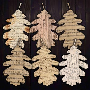 May include: A set of six decorative leaf-shaped cutouts made from vintage paper. The leaves feature printed designs including antique cursive handwriting, newspaper columns with New York text, and musical staff notation with notes.