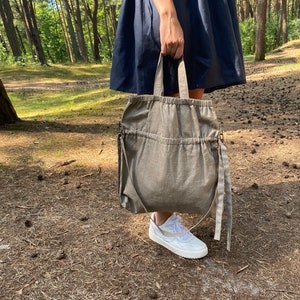 Natural linen color linen tote bag. Handmade from waxed linen. The bag is rectangular shape with short handles and shoulder strap, has inside pocket for phone and wallet. The tote bag closes with side straps. The shoulder strap is attached with darkened metal details and can be attached or removed.