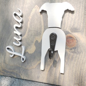 May include: White wooden dog-shaped coat hook with the name "Luna" written in white on a gray wooden background.
