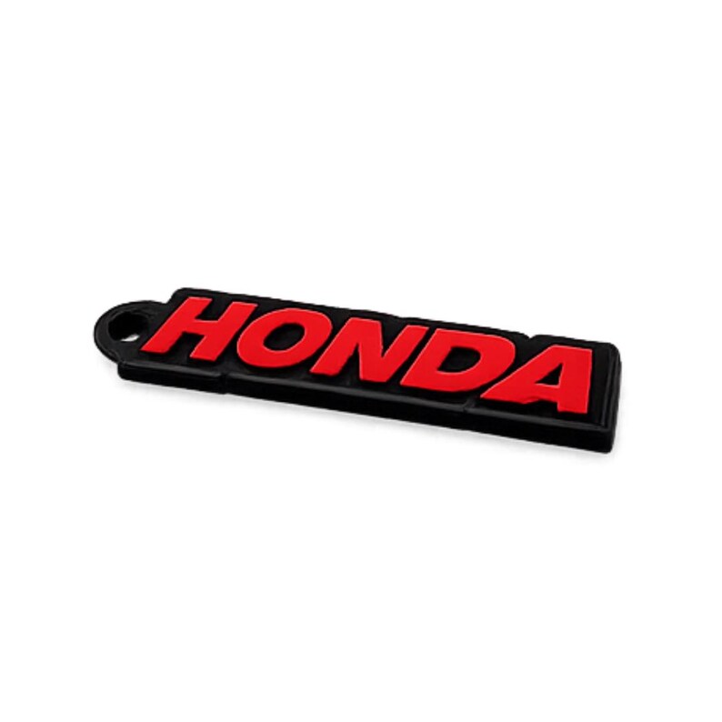 May include: Black and red Honda keychain. The word "HONDA" is in red, raised lettering against a black rectangular background. The keychain has a small, round hole at one end.