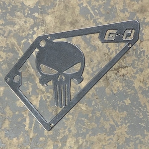 May include: A metal cutout of a skull with the text "G-D" in the upper right corner. The skull is in a diamond shape.