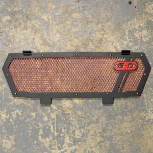 May include: Black metal grille with a red honeycomb pattern and a G-D logo.