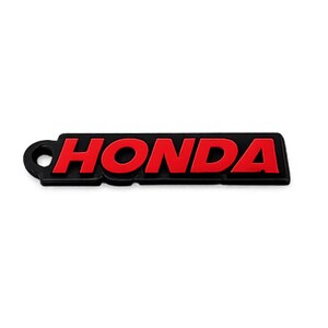 May include: Black and red Honda logo keychain. The word "HONDA" is in red, bold letters on a black rectangular background. The keychain has a small circular hole on the left side.