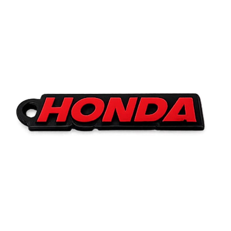 May include: Black and red Honda logo keychain. The word "HONDA" is in red, bold letters on a black rectangular background. The keychain has a small circular hole on the left side.