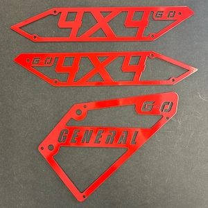 May include: Three red metal cutouts with the text "4x4" and "G-O" on two of the cutouts and "GENERAL" on the third cutout.