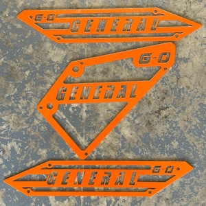 May include: Three orange metal signs with the text "G-O GENERAL" cut out. The signs are in different shapes and sizes.