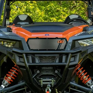May include: A black and orange off-road vehicle with a black mesh grille and a G-O logo. The vehicle has a black bumper and red coil springs.