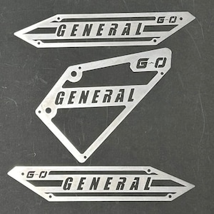 May include: Three metal plates with the word "GENERAL" and the letters "G-O" cut out. The plates are silver and have a brushed finish.