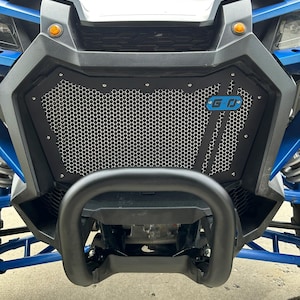May include: A black metal grille with a honeycomb pattern and a blue G-O logo. The grille is mounted on a blue and black off-road vehicle.