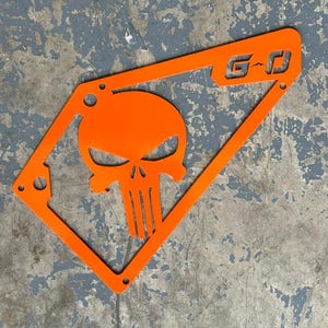 May include: Orange metal plate with a skull design and the letters "G-D" cut out.