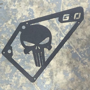 May include: Black metal plate with a cutout of a skull and the letters "G-D" in the upper right corner.