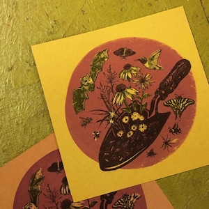 Peut inclure: Deux impressions illustrées sur fond jaune. Chaque impression présente un cercle avec une truelle de jardinage, des fleurs, des chauves-souris, des papillons et des abeilles. Le cercle est sur un fond rose.