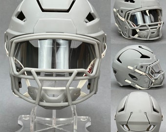 Op de afbeelding: Een grijze voetbalhelm met een helder vizier en witte banden. De helm staat op een heldere acryl displaystandaard.