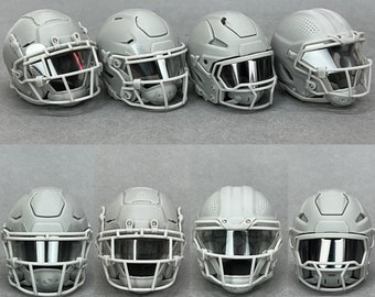 Op de afbeelding: Acht grijze voetbalhelmen met gezichtsmaskers en vizieren. De helmen hebben een gestructureerd oppervlak en zijn gerangschikt in twee rijen van vier.