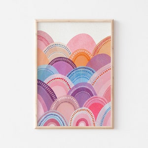 May include: Watercolour art print depicting an abstract landscape. The artwork presents layered, semi-circular shapes in pink, purple, blue, and orange hues, with dotted and striped details. The print is framed in a light wood frame.