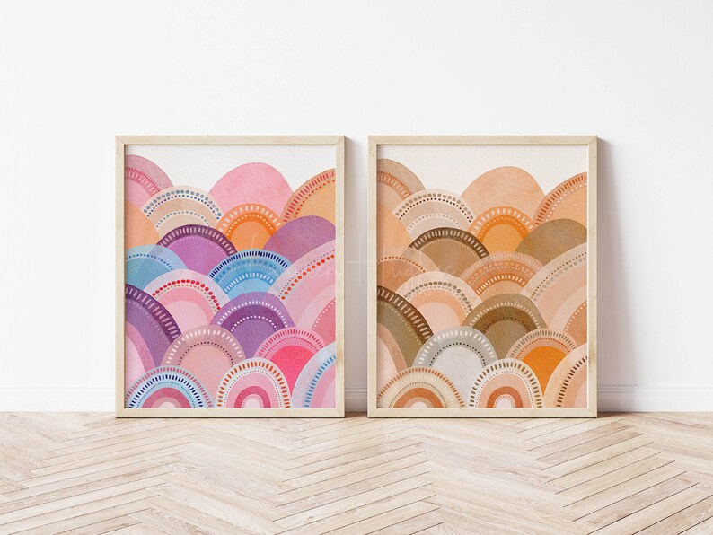 May include: Two framed watercolour prints. One shows a colourful array of pink, purple, blue, and orange semi-circles with dotted details. The other displays a similar design in warm earth tones of brown, tan, and orange. Both are in light wood frames.