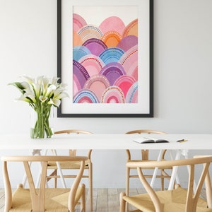 May include: A framed watercolour print with an abstract design of layered, semi-circular shapes in pink, purple, blue, and orange. The artwork is in a black frame, adding a modern touch. The room also features a white table and wooden chairs. The table is 150 cm long.