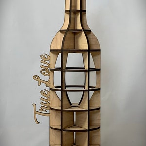 May include: A wooden wine bottle rack with a cutout design. The rack is made of light brown wood with dark brown accents. The words "True Love" are written on the side of the rack.