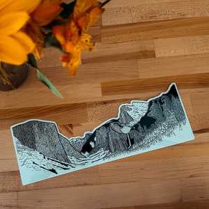 May include: A black and white line drawing of Yosemite National Park's Half Dome, El Capitan, and Bridalveil Fall. The drawing is on a light blue background.