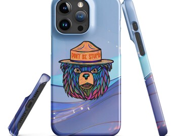 May include: A light blue phone case featuring a colorful bear wearing a ranger hat with the text "DON'T BE STUPID". The case has a glossy finish and a wraparound design with a blue and purple wave pattern.