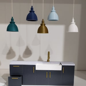 May include: A dark gray kitchen cabinet with a white farmhouse sink and gold hardware. Five pendant lights hang above the cabinet, including teal, blue, gold, and white.