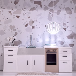 May include: White kitchen cabinets with a farmhouse sink, a brown oven, and a white round pendant light hanging above. The cabinets have black handles and the backsplash is a white and brown terrazzo pattern.