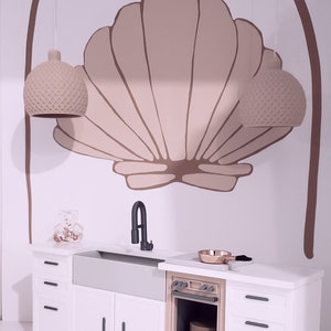 May include: A white kitchen with a farmhouse sink, a beige oven, and white cabinets. The backsplash features a large, painted seashell design with two hanging light fixtures.