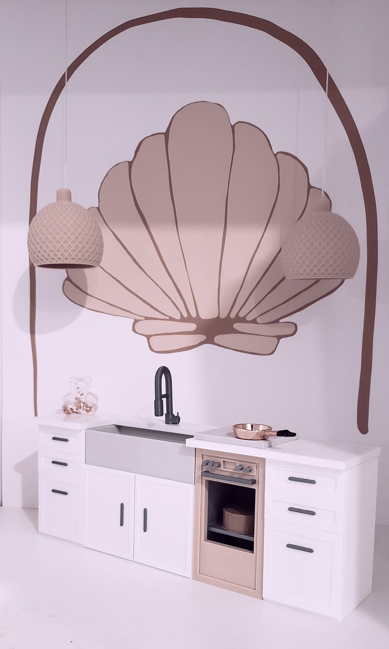 May include: A white kitchen with a farmhouse sink, a beige oven, and white cabinets. The backsplash features a large, painted seashell design with two hanging light fixtures.