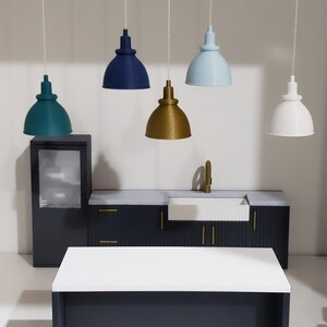 May include: A miniature kitchen set with a white countertop, dark blue cabinets, and a white sink. Five pendant lights hang above the countertop, each with a different colored shade: teal, navy blue, gold, light blue, and white.