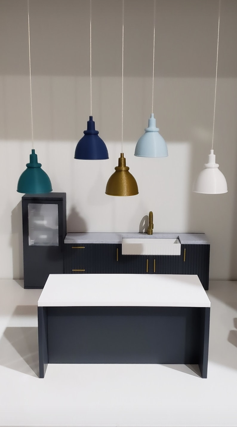 May include: A miniature kitchen set with a white countertop, dark blue cabinets, and a white sink. Five pendant lights hang above the countertop, each with a different colored shade: teal, navy blue, gold, light blue, and white.