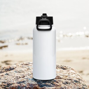 Op de afbeelding: Een witte cilindervormige waterfles met een gladde afwerking en een zwarte schroefdop met een geïntegreerde draagbeugel. De fles heeft een recht ontwerp met een platte bodem, wat zorgt voor een strakke en eenvoudige uitstraling voor dagelijks gebruik.