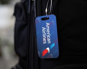 May include: A black luggage bag with a blue and red American Airlines luggage tag attached to it.