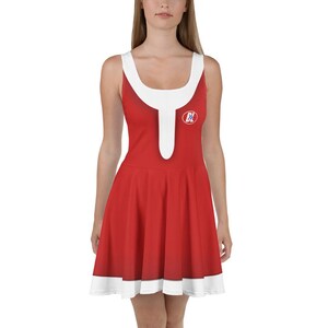 Pode incluir: Um vestido vermelho e branco sem mangas com uma gola branca e um círculo branco com as letras "BL" em azul na frente.