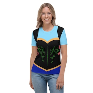 May include: A blue, black and gold women's t-shirt with a stylised floral design. The shirt features a light blue bodice with a gold trim and a black skirt with a blue trim.