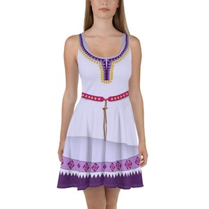 May include: A white sleeveless dress with a purple and gold geometric pattern. The dress has a pink belt and a layered skirt.