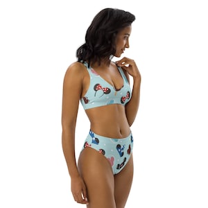 Könnte beinhalten: Ein hellblauer Bikini mit einem hoch sitzenden Höschen. Der Bikini ist mit einem Muster aus Mickey-Maus-Ohren, Hüten und Eisbechern bedruckt.