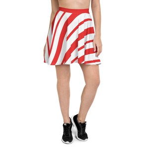 May include: A skater skirt with a bold red and white striped pattern. The skirt features a high waist and a flared silhouette. The stripes are wide and evenly spaced, creating a visually striking design. The skirt is worn with black sneakers.