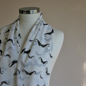 Op de afbeelding: Witte sjaal met een zwart en grijs snorrenpatroon.