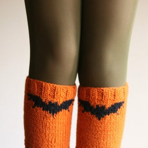 Peut inclure: Jambières en tricot orange avec un motif de chauve-souris noire. Ces jambières sur le thème d'Halloween sont un accessoire confortable et festif. Les jambières sont faites d'un tissu tricoté doux et texturé.