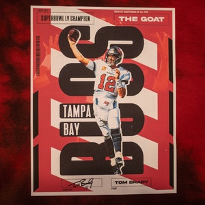 May include: A red and white graphic design with a photo of Tom Brady in a Tampa Bay Buccaneers uniform. The text "2020-2021 Superbowl LV Champion" and "The Goat" are included in the design.