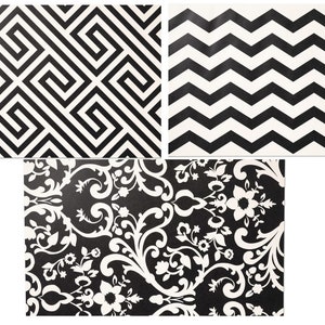 May include: Three black and white patterned fabric swatches. The first swatch has a geometric pattern of intersecting lines. The second swatch has a chevron pattern. The third swatch has a floral pattern.