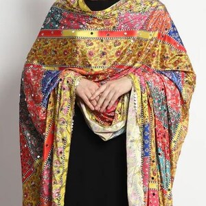 May include: A yellow, red, blue, and green patterned silk scarf with a beaded border. The scarf is draped over a person's shoulders.