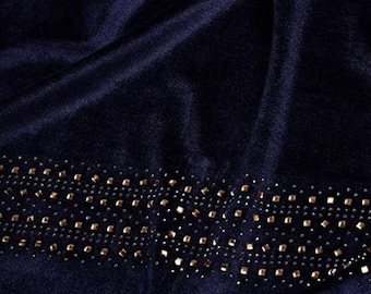 Puede incluir: Tela de terciopelo azul oscuro con un ribete decorativo de pedrería dorada.
