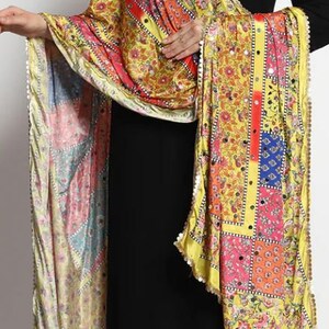 May include: A yellow, pink, blue, and red patterned silk scarf with gold trim and mirror embellishments.