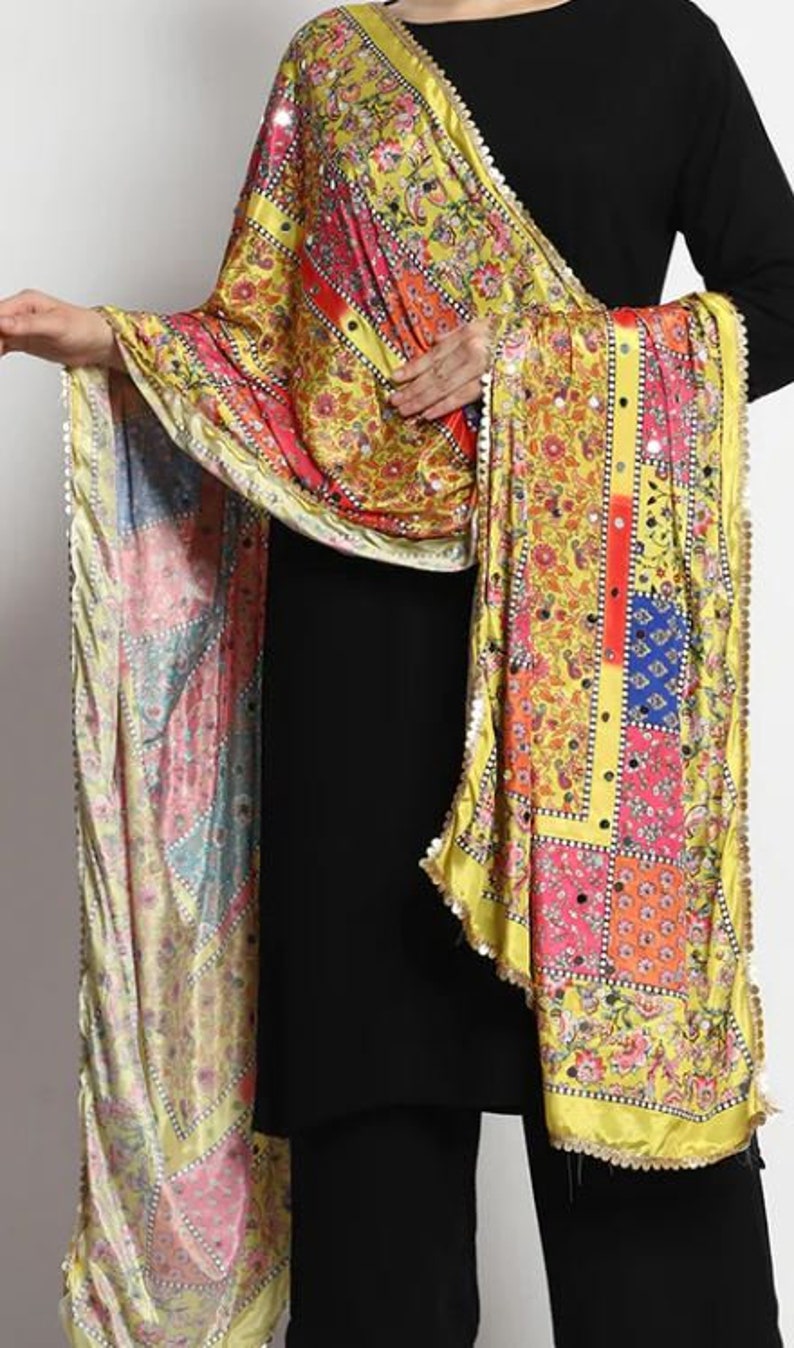 May include: A yellow, pink, blue, and red patterned silk scarf with gold trim and mirror embellishments.