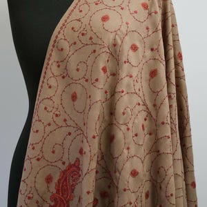 May include: A brown shawl with red embroidery featuring a paisley design and intricate floral patterns.